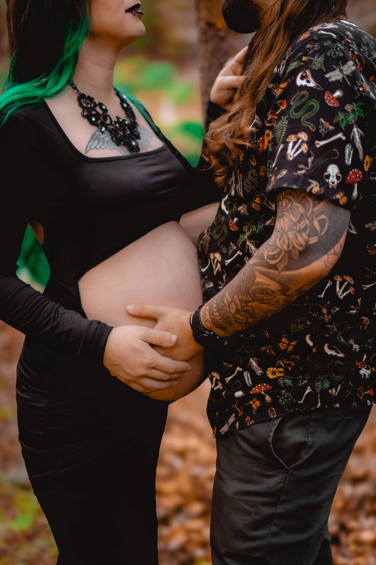 A pregnant woman with green hair standing next to a man